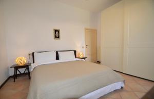 a white bedroom with a large bed with two lamps at Villa Cassiani in Fiorenzuola di Focara +44 photos