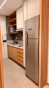 a stainless steel refrigerator in a kitchen with wooden cabinets at Novíssimo Flat Beach Class Solare - Muro Alto -Soft Open in Porto De Galinhas