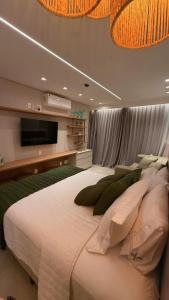 a bedroom with a large bed and a flat screen tv at Novíssimo Flat Beach Class Solare - Muro Alto -Soft Open in Porto De Galinhas