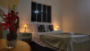 a bedroom with a bed with a table and two lamps at Pousada Flor do Campo in Serra do Cipo