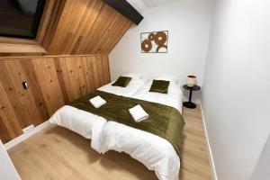 a bedroom with a large white bed with green sheets at Maison Connectée Serenia in Méru