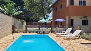 a pool with chairs and umbrellas next to a house at Pousada Flor do Campo in Serra do Cipo