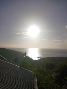 a view of the ocean with the sun in the sky at La plus grande source d'eaux chaudes F1 in Bouillante