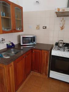 a kitchen with a sink and a stove and a microwave at Vallesito in Salsipuedes