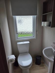 a small bathroom with a toilet and a window at Poole Rockley Park Dorset in Poole +8 photos