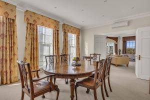 a dining room with a wooden table and chairs at Castle by the Sea - Tilba Road 26 in Bermagui