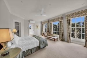 a bedroom with a bed and a couch and windows at Castle by the Sea - Tilba Road 26 in Bermagui
