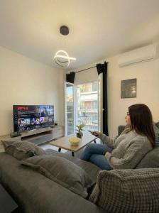 a woman sitting on a couch playing a video game at White Port Suite in Ágios Rókkos
