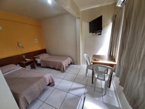 a hotel room with two beds and a desk and a television at Ambassador Hotel in Foz do Iguaçu +15 photos