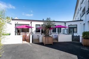 a white building with pink umbrellas in the courtyard at Koaloft - Terrasse privée - Lorient centre in Lorient