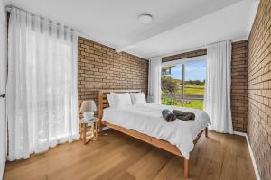 a bedroom with a bed and a brick wall at Fishers - Scenic Drive 35 in Bermagui