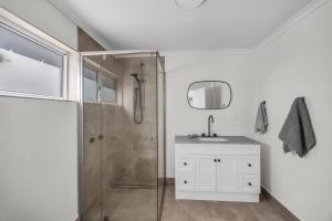 a bathroom with a shower and a sink and a mirror at Fishers - Scenic Drive 35 in Bermagui +33 photos