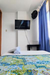 a bedroom with a bed with a flat screen tv on the wall at Hotel Real, Villa Garzón in Villagarzón