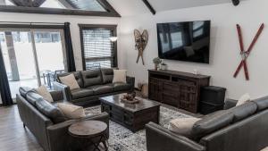 a living room with leather couches and a tv at Polar Den Cabin in Valemount