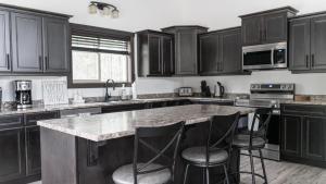 a kitchen with black cabinets and a island with bar stools at Polar Den Cabin in Valemount