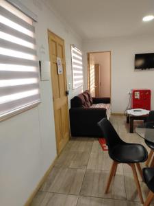 a living room with a black couch and a table at Cabañas Haru Puerto Natales in Puerto Natales