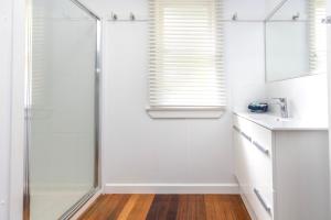 a white bathroom with a shower and a sink at Koala Lodge Cottage 5 in Iluka +7 photos