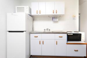 a white kitchen with a sink and a refrigerator at Koala Lodge Studio 2 in Iluka