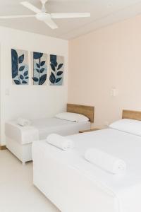 a white room with two beds and a painting at Quinta en Melgar piscina BBQ cerca a Piscilago in Melgar +27 photos