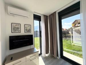 a living room with a tv and a large window at Villa Maja in Trebinje