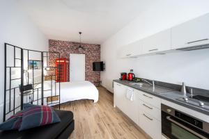 a kitchen with white cabinets and a bed in a room at Koaloft - Terrasse privée - Lorient centre in Lorient