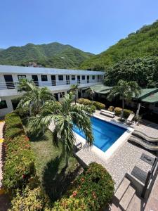 a resort with a pool and palm trees and a building at La Masia Hostal in Taganga