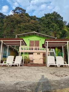 a green house with white chairs in front of it at Ofiuras Hostal in Colón
