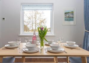 a wooden table with plates and glasses and a vase of flowers at 38 Venn Park in Stoke Fleming +18 photos