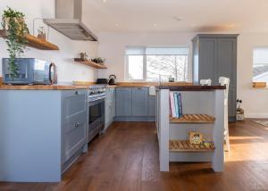 a kitchen with blue cabinets and a wooden floor at 38 Venn Park in Stoke Fleming