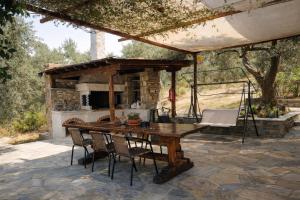 an outdoor dining area with a wooden table and chairs at Villa Belian 1 in Argalasti