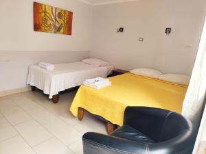 a room with two beds and a chair in it at Hotel Marluz in Mejillones