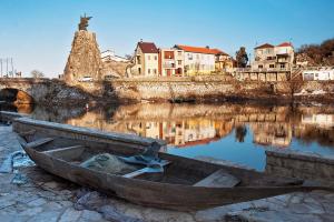 a wooden boat sitting on the shore of a river at Pink bird apartments and FREE PARKING in Virpazar
