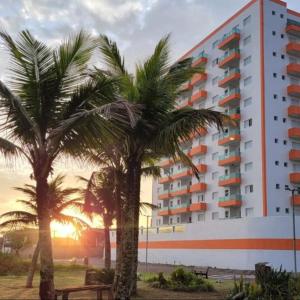 a large building with palm trees in front of it at Apto 83 in Itanhaém