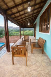 two wooden benches sitting on a porch with a view at Sítio Anna in São Thomé das Letras