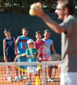 a group of young children standing on a tennis court at Chia Laguna - Hotel Village in Chia
