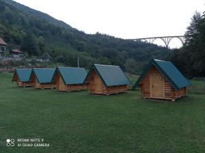 a row of wooden cabins with green roofs in a field at Camp Budečevica in Žabljak