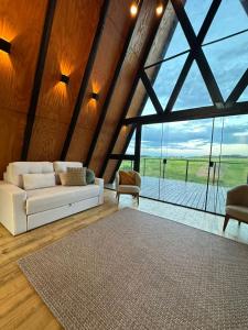 a living room with a white couch and a large window at Chalé Aurora - Sebollas - Paraíba do Sul in Paraíba do Sul