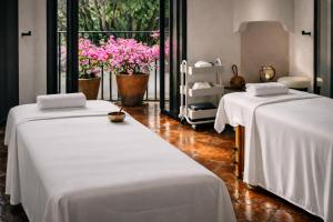 two beds with white sheets in a room with flowers at Las Casas B&B Boutique Hotel, Spa & Restaurante Cuernavaca in Cuernavaca