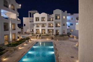 a swimming pool in front of a building at night at Arian North Coast Chalet Santorini Resort El Alamein in El Alamein