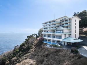 an apartment building on a cliff next to the ocean at IZU RETREAT ATAWAGA SUIKO by Onko Chishin in Higashiizu
