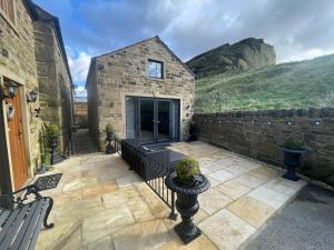a stone house with a courtyard with a bench at The Old Quarry Hideaway in Cowling