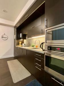 a kitchen with black cabinets and a microwave at Luxurious Condo Apartment with Direct Subway Access in Toronto