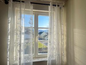 a window with white curtains and a view of a house at Ferienwohnung Sonnentälchen in Konz