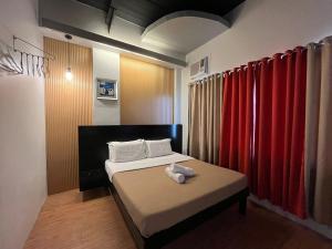 a small room with a bed and red curtains at First Pacific Inn Davao in Davao City