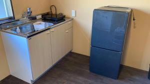 a kitchen with a blue refrigerator next to a sink at Kominka Himejuku in Tajimi