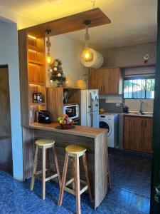 a kitchen with a counter with stools and a refrigerator at Hospedaje Rural León in Encarnación
