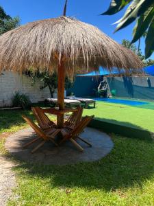 two chairs under a straw umbrella in a yard at Hospedaje Rural León in Encarnación