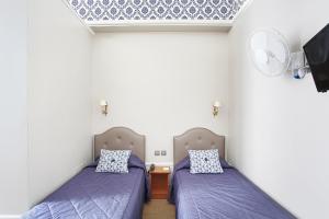 Cette chambre comprend 2 lits avec des draps violets et une télévision. dans l'établissement Hotel Montpensier, à Paris 37 autres photos