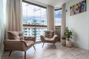 a living room with two chairs and a large window at Caribe Carioca in Rio de Janeiro