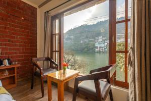 a room with a table and chairs and a large window at By the Lake Boho Bhimtal in Bhīm Tāl